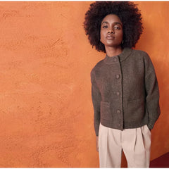 Woman wearing a brown knitted cardigan against an orange wall