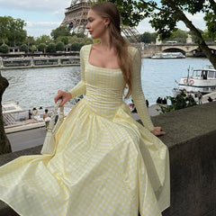 Woman in a yellow dress sitting by the Seine river with the Eiffel Tower in the background