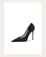 Black high-heeled shoe with studded details on a white background