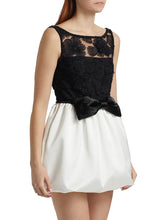 Black lace top and white skirt dress on a model against a white background