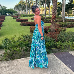 Woman in a blue floral dress standing in a garden with palm trees