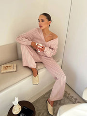 Woman in a pink outfit sitting on a couch in a minimalistic room.