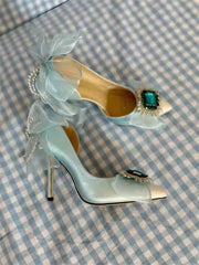 Teal high-heeled shoe with decorative elements on a checkered fabric background