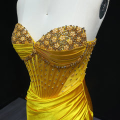 Yellow evening gown with bead embellishments on a mannequin against a black background