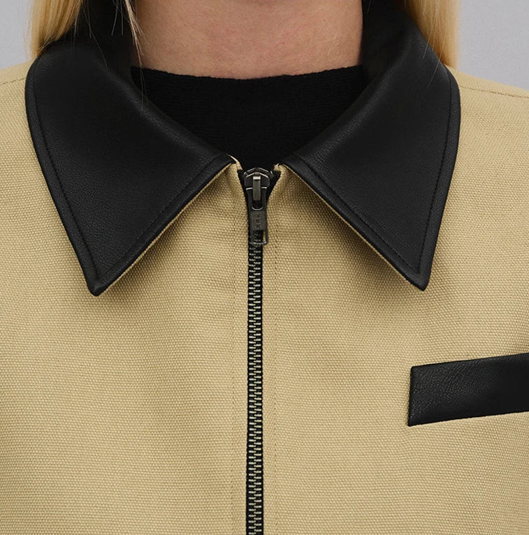 Close-up of a beige jacket with black collar and zipper
