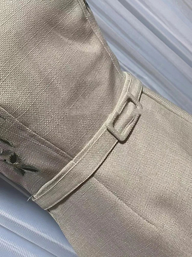Close-up of beige pants with a belt on a light blue background