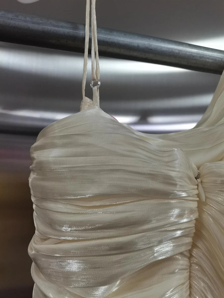 Close-up of a beige pleated fabric hanging against a metallic background