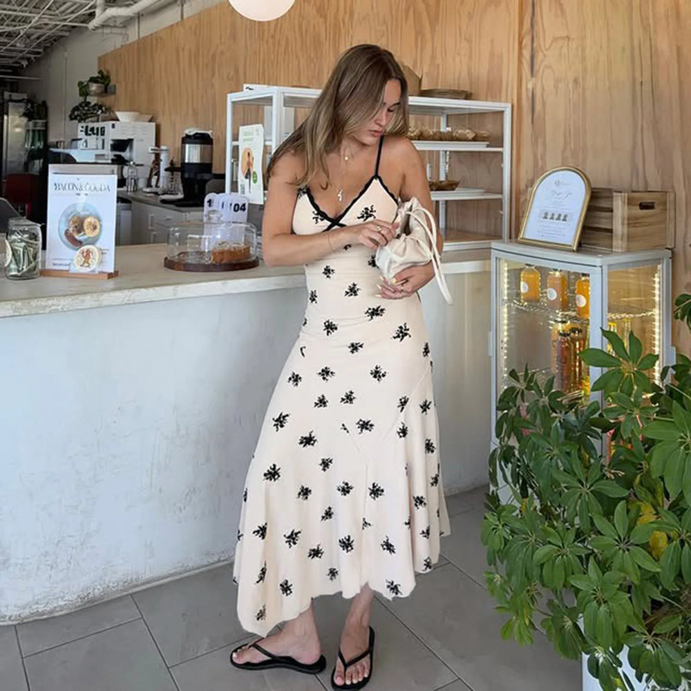 Woman in a white dress with black patterns standing in a cafe.