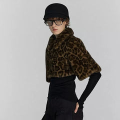 Person wearing a leopard print fur shrug over a black outfit on a plain background
