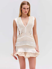 Woman wearing a beige crochet top and shorts on a light gray background