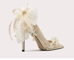 Delicate high-heeled shoes with floral and ribbon details on a light background