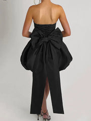 Black strapless dress with a large bow detail on a plain background