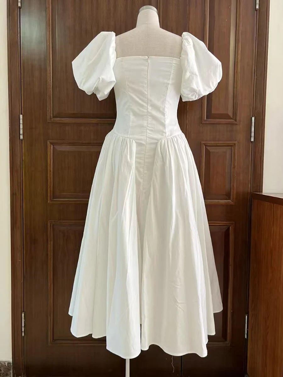 White dress with puffed sleeves on a mannequin against a wooden door background