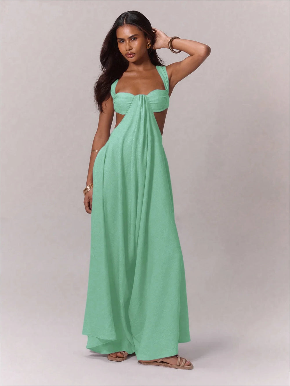 Woman wearing a mint green strapless jumpsuit against a plain background