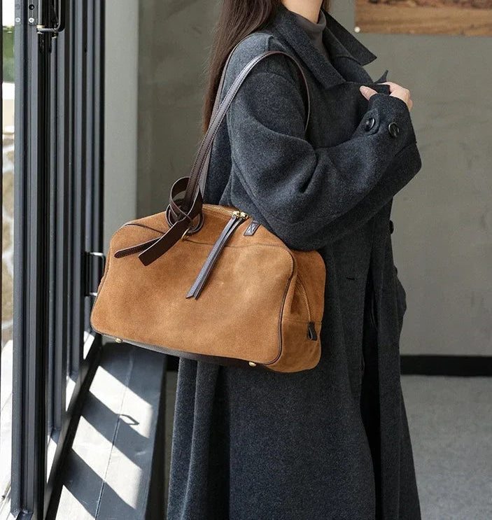 Woman holding a brown leather bag in an indoor setting