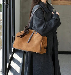 Woman holding a brown leather bag in an indoor setting