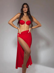 Full-body view of a model wearing a red ribbed underwire bikini and high-slit maxi skirt.