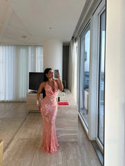 Woman in a pink sequin dress standing in a modern room with large windows.