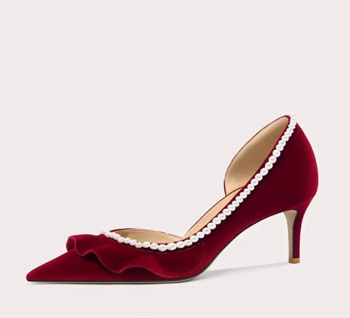 Red high-heeled shoe with pearl details on a light gray background