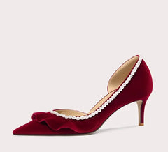 Red high-heeled shoe with pearl details on a light gray background