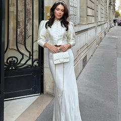 Woman in a white outfit standing on a city street