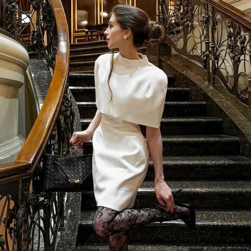 Woman in a white dress standing on a staircase in an elegant interior setting