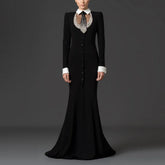 Model wearing a black floor-length dress with a white collar and beaded embellishment.
