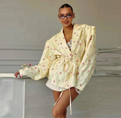 Woman wearing a light-colored floral robe against a neutral background