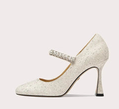 Sparkly high-heeled shoe with a decorative strap on a light gray background