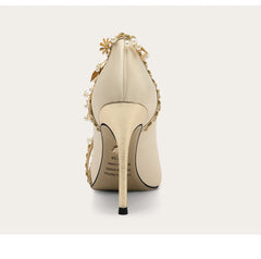 Beige high-heeled shoe with decorative elements on a white background