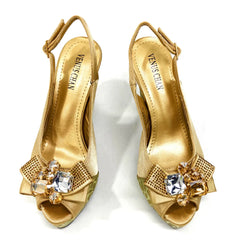 Gold high-heeled shoes with gemstones on a white background