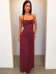 Woman wearing a burgundy halter neck gown against a plain background
