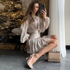 Woman in a white dress taking a mirror selfie in a decorated room.