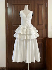 White ruffled dress on a mannequin against a wooden door.