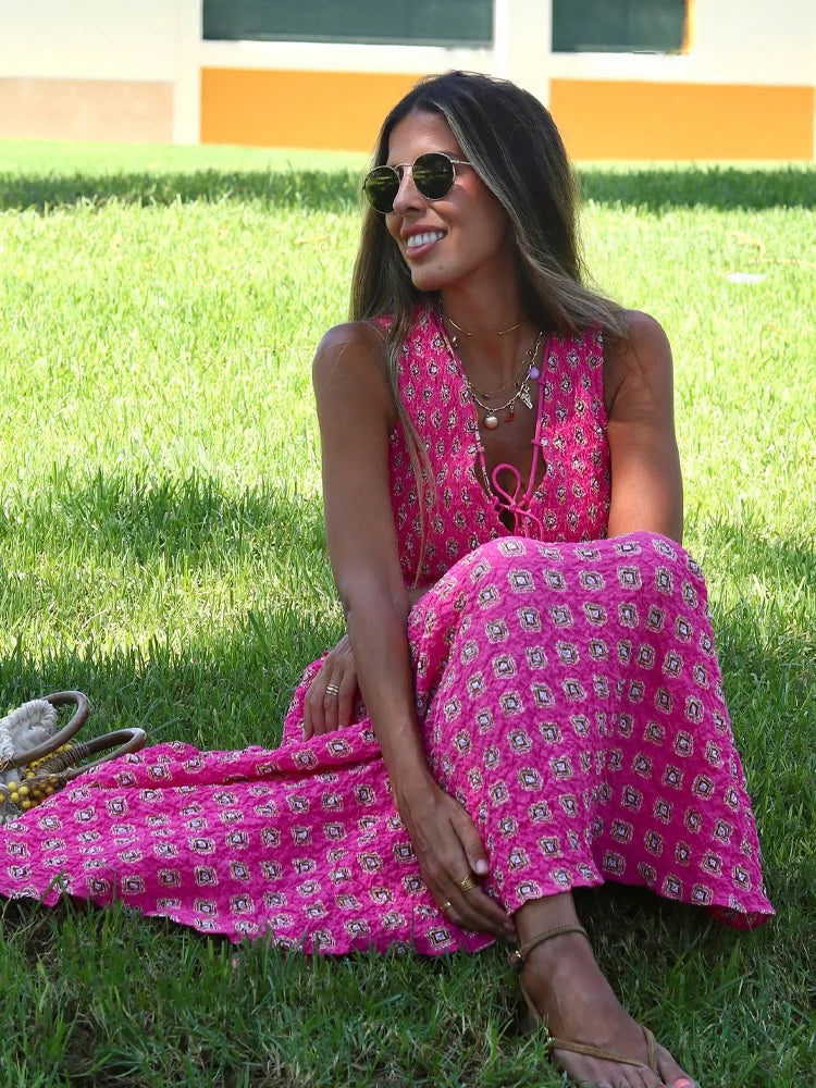 Woman in a pink floral dress sitting on grass