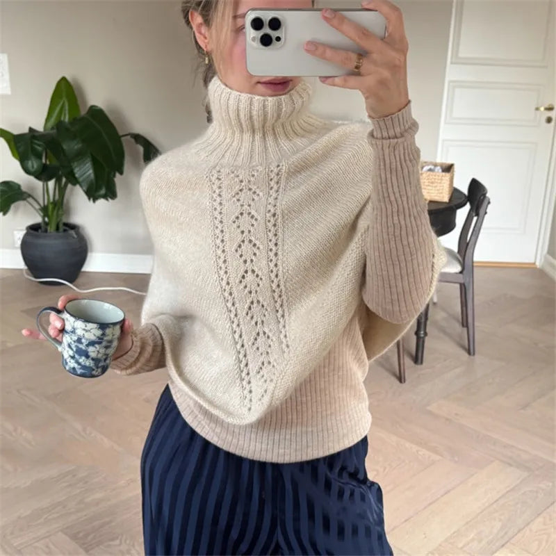 Model wearing a beige knit poncho with turtleneck and fringe