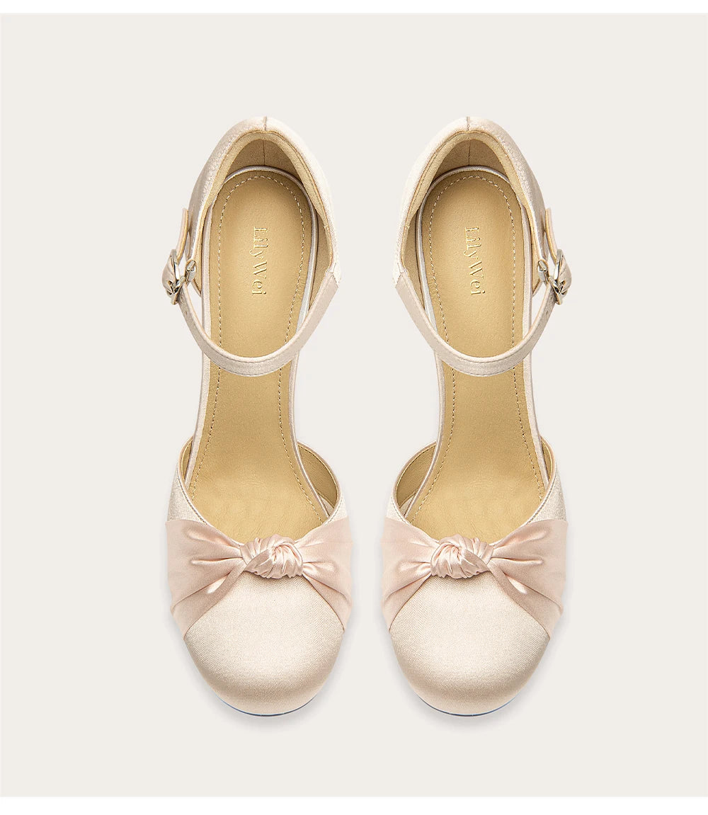 Pair of beige high heels with bow details on a white background