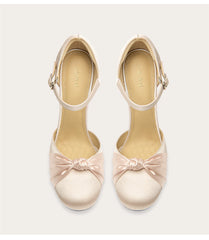 Pair of beige high heels with bow details on a white background