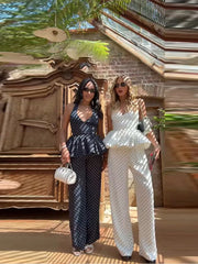 Two women in matching polka dot outfits standing in front of a decorative wall.
