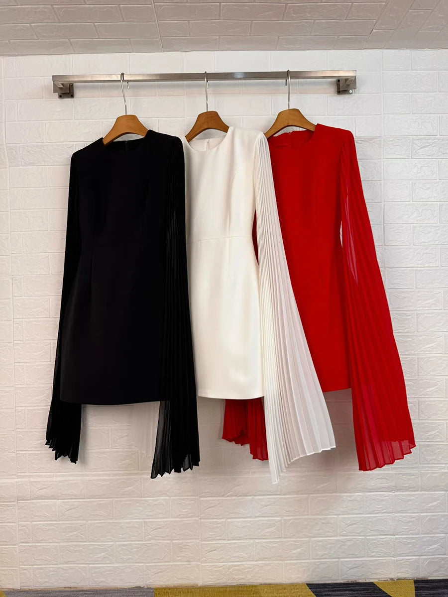 Black, white, and red mini dresses with pleated cape sleeves on hangers
