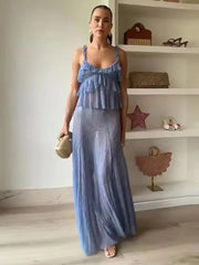 Woman wearing a blue dress standing in a room with shelves in the background