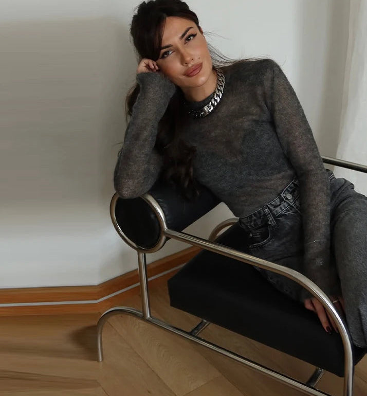 Woman sitting on a modern chair in a minimalistic room.