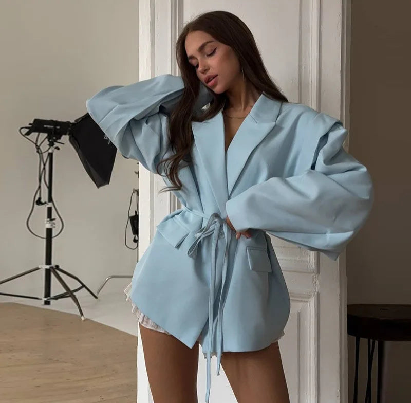 Woman wearing a light blue robe in a studio setting with photography equipment.