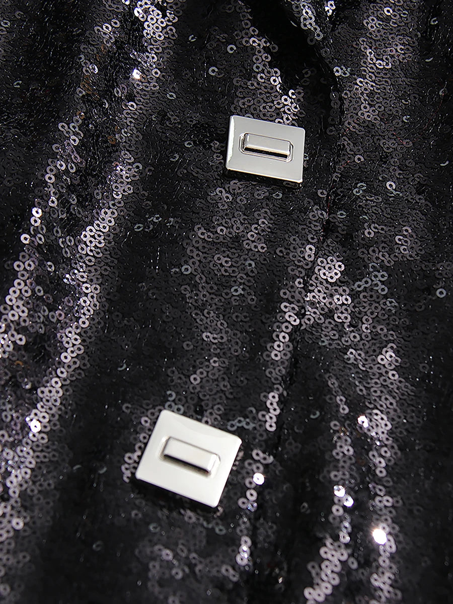 Close-up of black sequin fabric with two silver buttons on a dark background