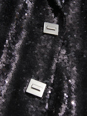 Close-up of black sequin fabric with two silver buttons on a dark background