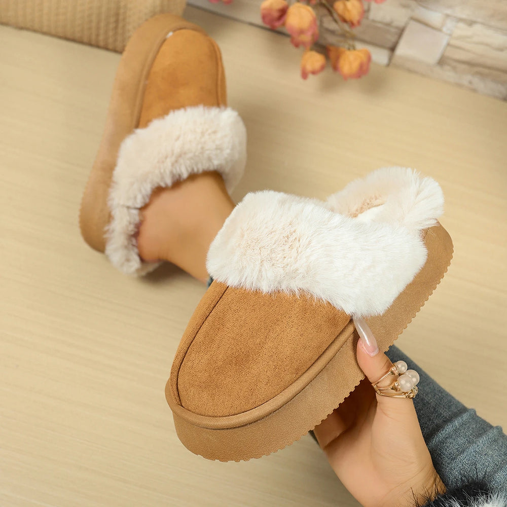 Brown slippers with white fur lining held by a hand on a beige surface.
