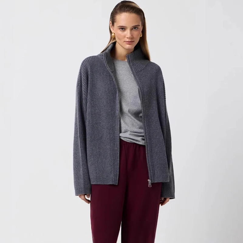 Woman wearing a gray cardigan over a gray shirt with burgundy pants on a white background