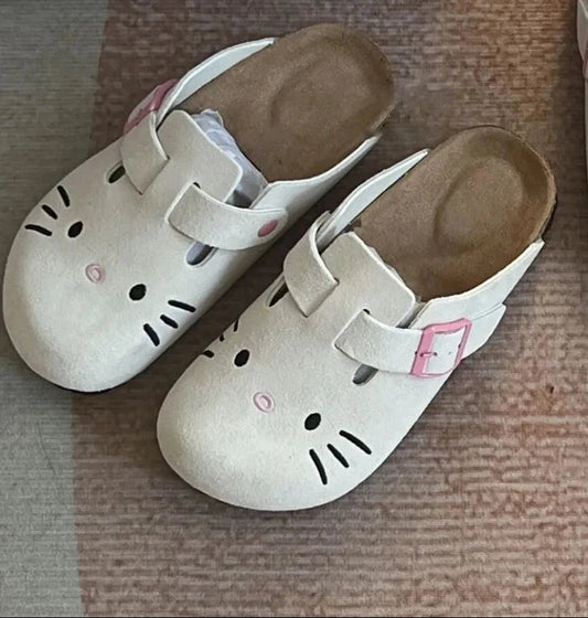 White Hello Kitty flat mule slippers with pink buckle straps and embroidered face.