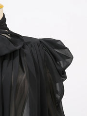 Black fabric with a draped design on a mannequin against a white background