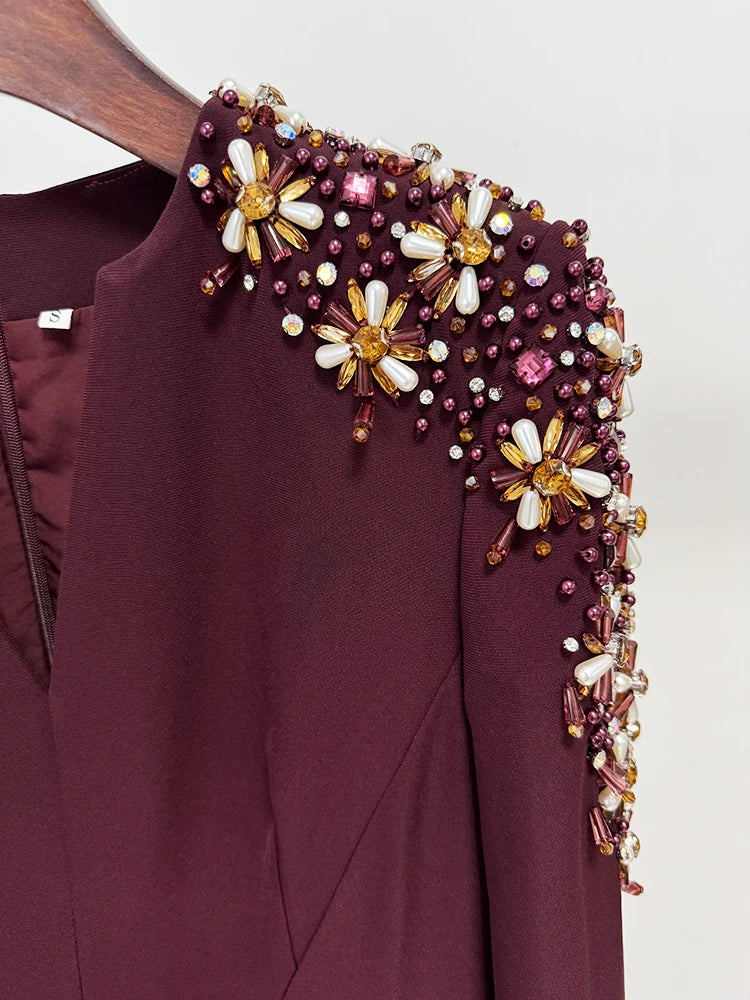 Maroon garment with floral bead embellishments on a plain background